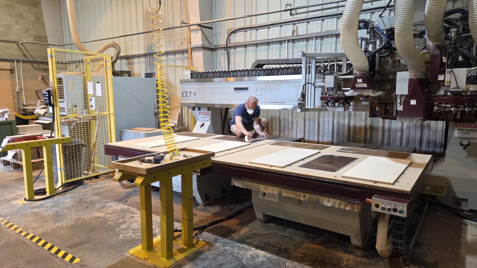 CNC operator programming the router cutting birch plywood speaker cabinet panels.