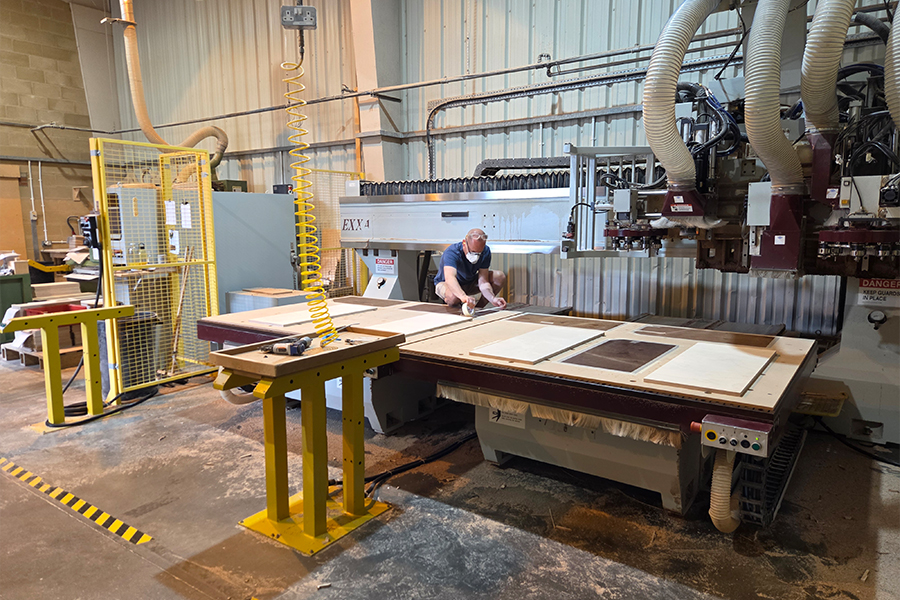 A CNC router cutting a Baltic Birch panel to acoustic tolerances.